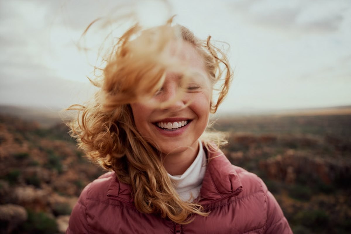 A woman smiling with her eyes closed outdoors